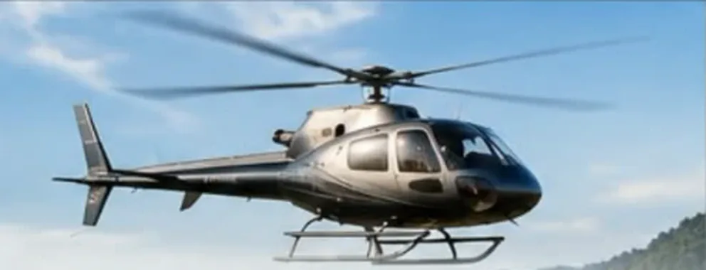 Elicottero Airbus H125 grigio scuro in volo nel cielo azzurro