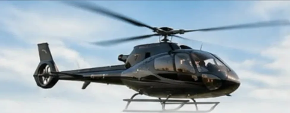Elicottero Airbus H130 nero in volo nel cielo azzurro